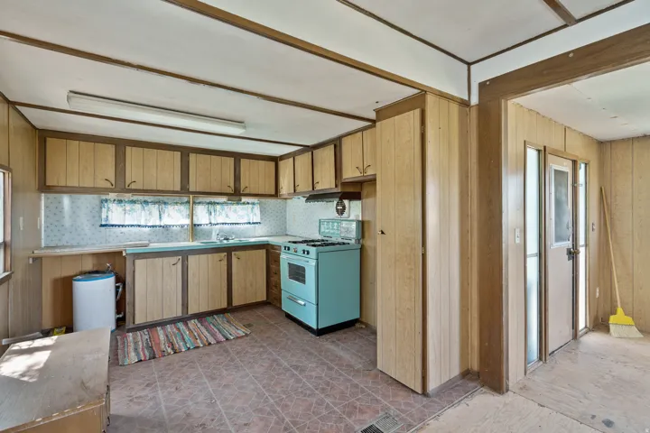 Kitchen with range with gas stovetop, healthy amount of natural light, wooden walls, backsplash, and light countertops