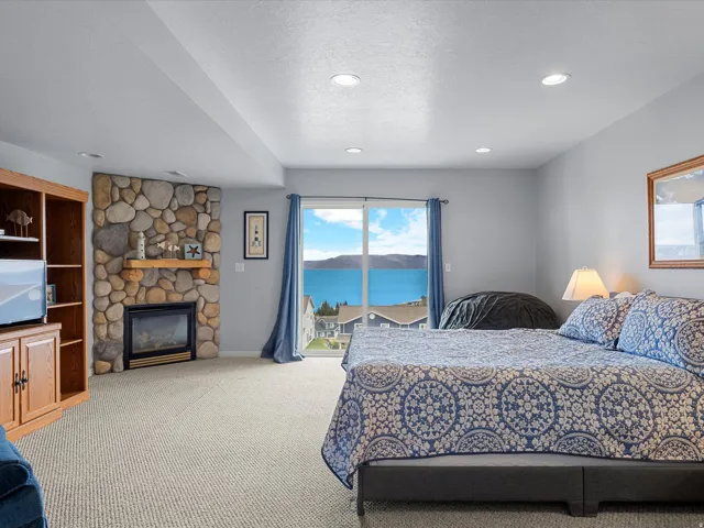 Bedroom with a textured ceiling, access to exterior, a stone fireplace, carpet, and recessed lighting