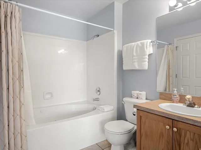 Bathroom with vanity, shower / bath combination with curtain, and light tile patterned floors