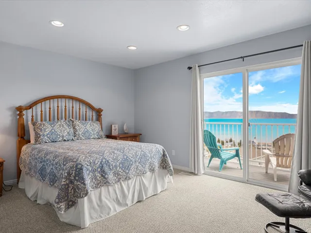 Bedroom with light colored carpet, recessed lighting, a water and mountain view, and access to exterior