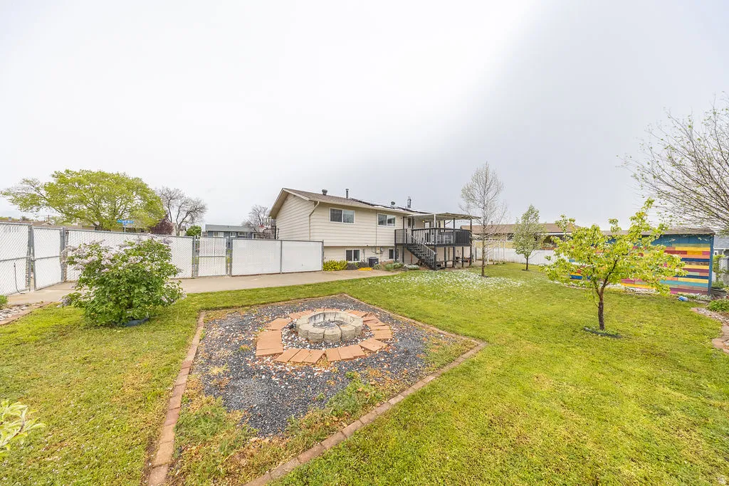 Fenced backyard with a gate, an outdoor fire pit, a deck, and a patio