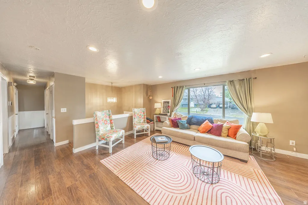 Living room featuring dark wood-style floors, a textured ceiling, and recessed lighting