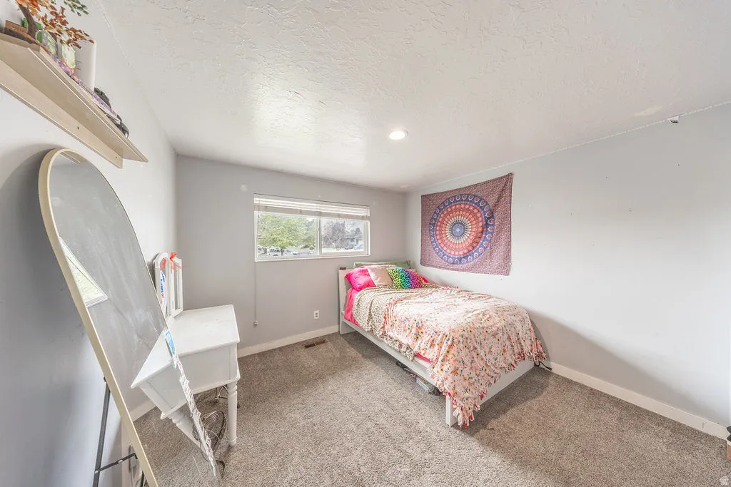 Bedroom featuring a textured ceiling and light colored carpet