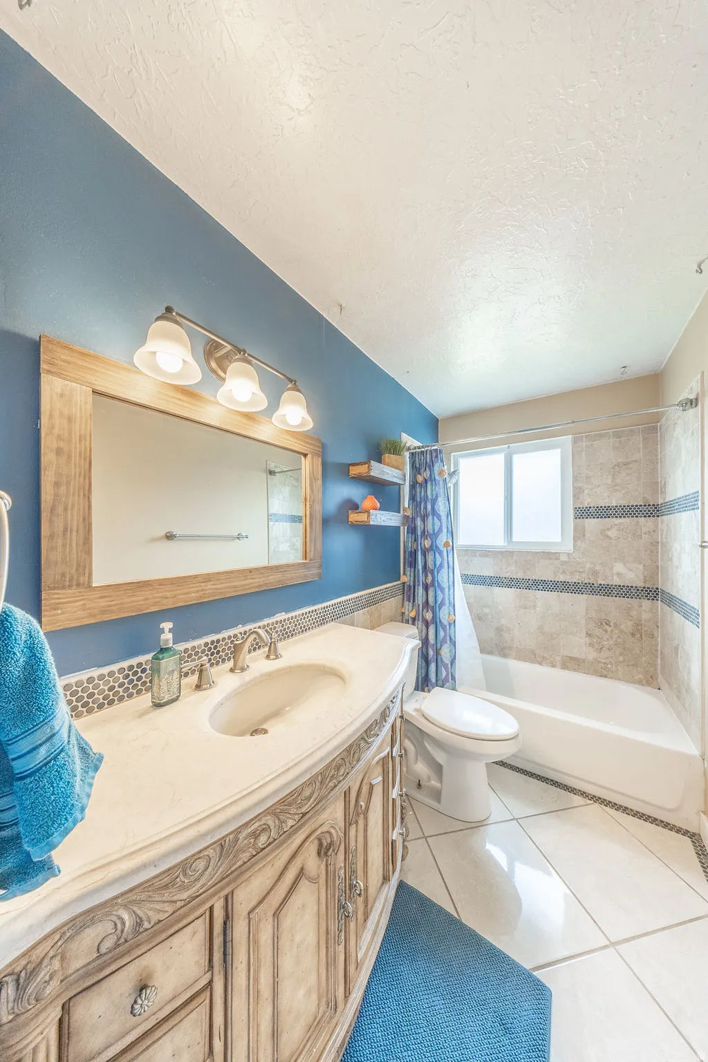 Full bath with vanity, light tile patterned floors, shower / tub combo with curtain, and a textured ceiling
