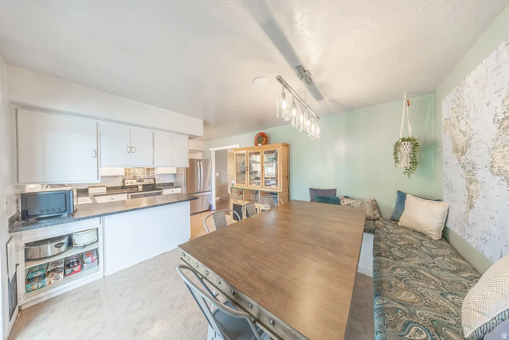 Dining area featuring light floors, suspended lighting, and a textured ceiling
