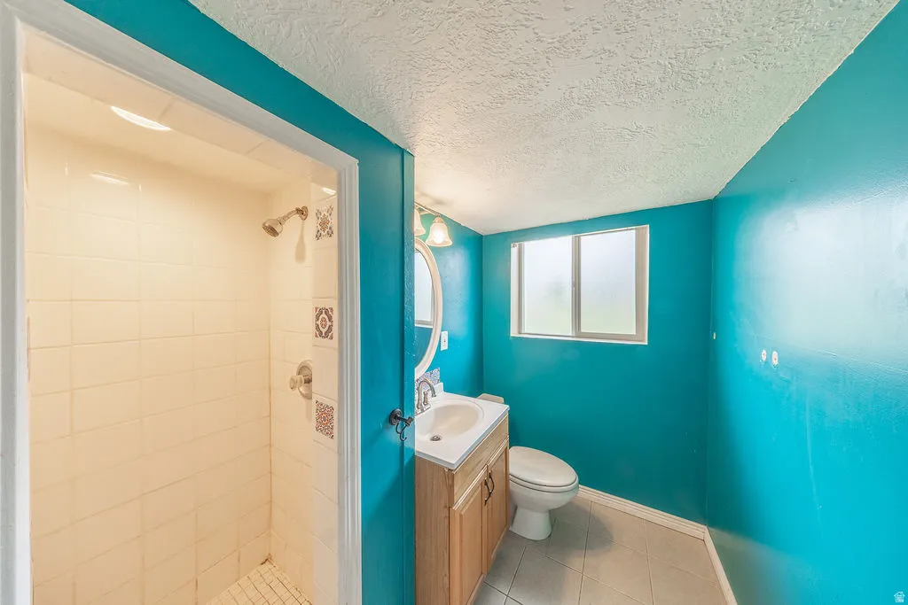 Full bathroom with a textured ceiling, vanity, a stall shower, and light tile patterned floors
