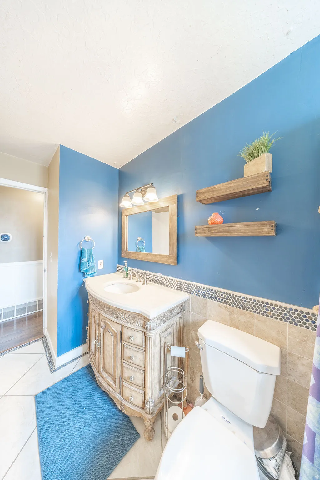 Bathroom with a wainscoted wall, vanity, light tile patterned floors, and tile walls