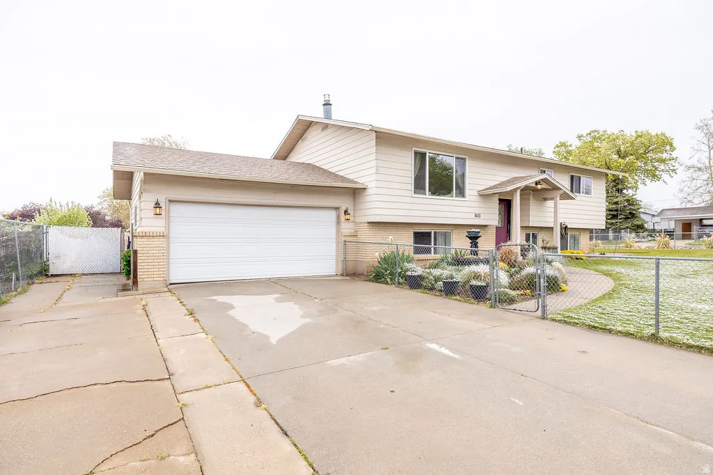 Bi-level home with a gate, brick siding, driveway, and a garage