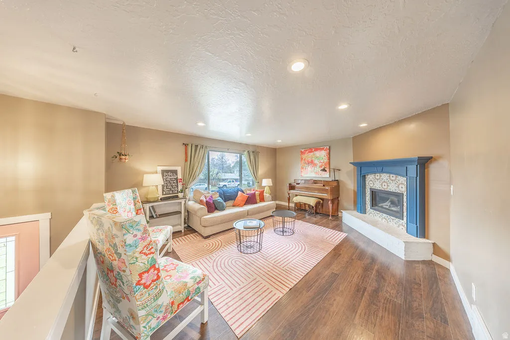 Living area featuring wood-type flooring, recessed lighting, a textured ceiling, and a glass covered fireplace