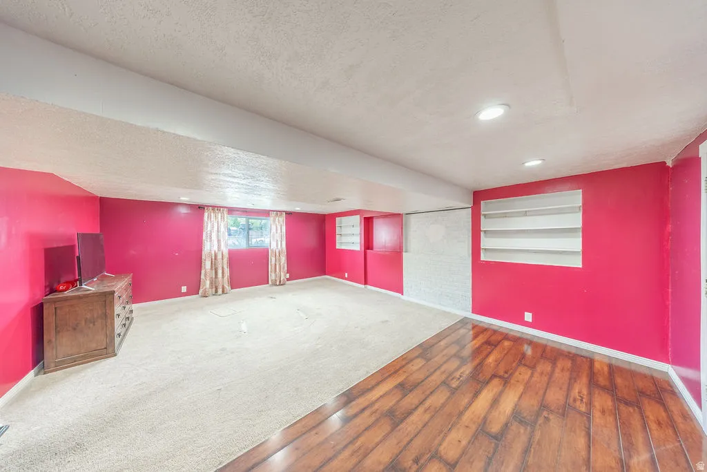 Carpeted empty room featuring a textured ceiling, hardwood / wood-style floors, and built in features