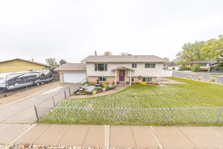 Split foyer home featuring a fenced front yard, a garage, and concrete driveway