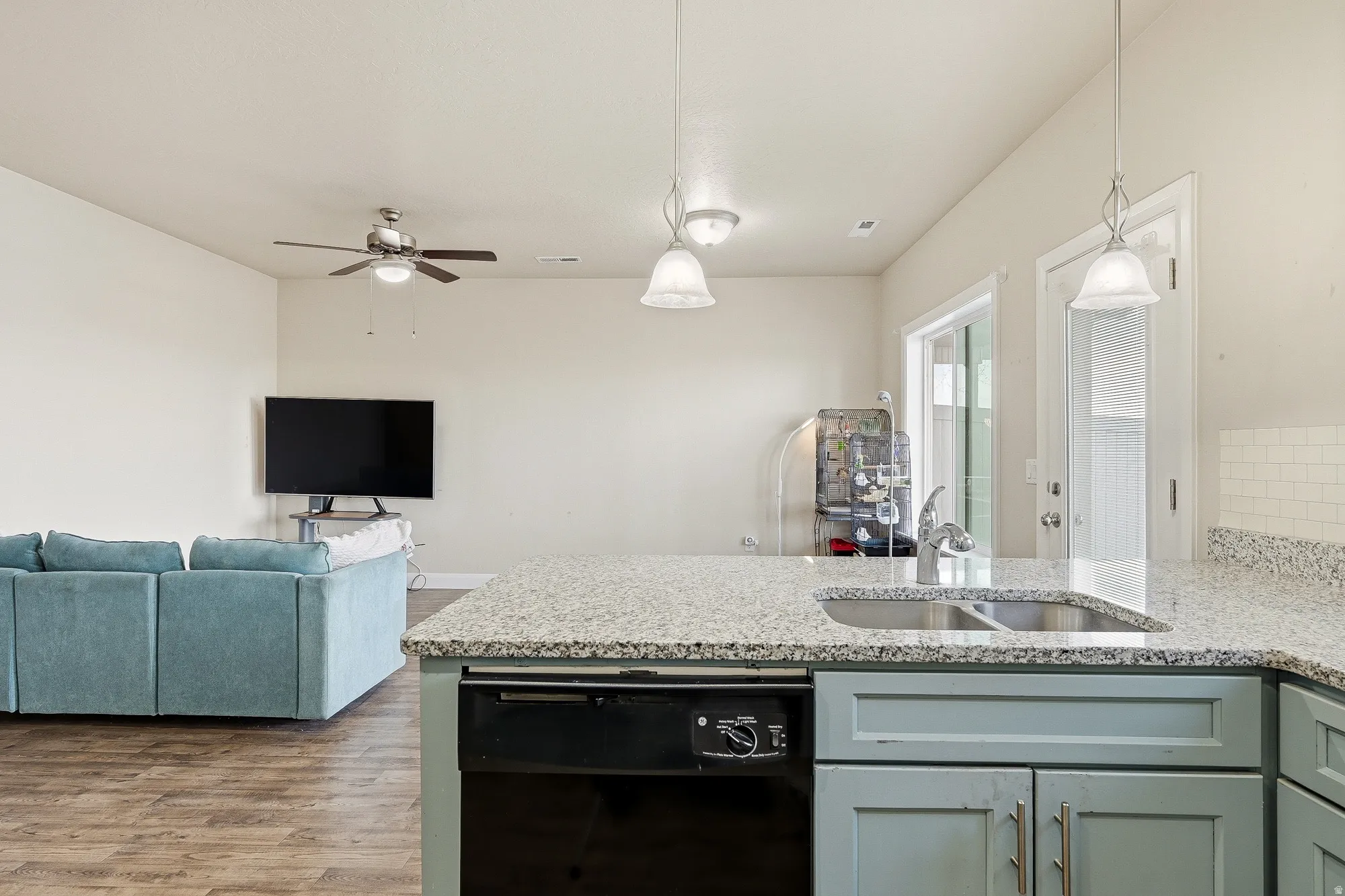Kitchen with a peninsula, black dishwasher, light stone counters, open floor plan, and dark wood finished floors