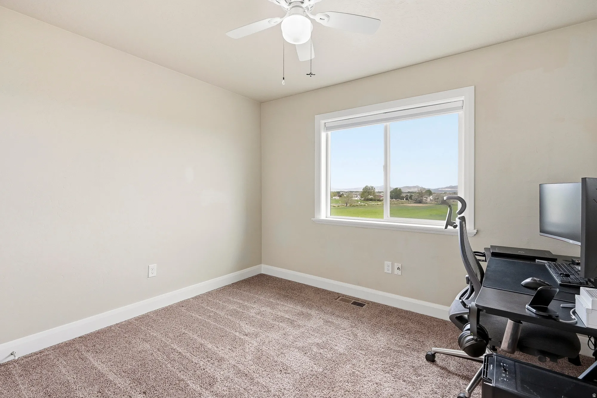 Carpeted room with a ceiling fan light fixture and a double-pane window