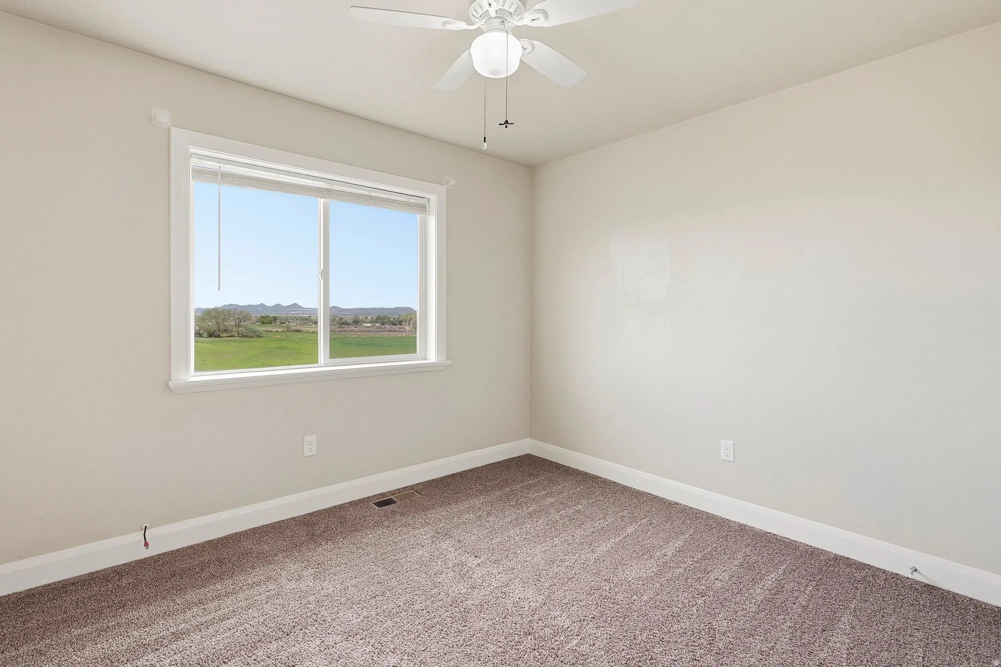 Interior room featuring an expansive window with white trim, a ceiling fan with integrated lighting, neutral wall tones, and plush carpeting