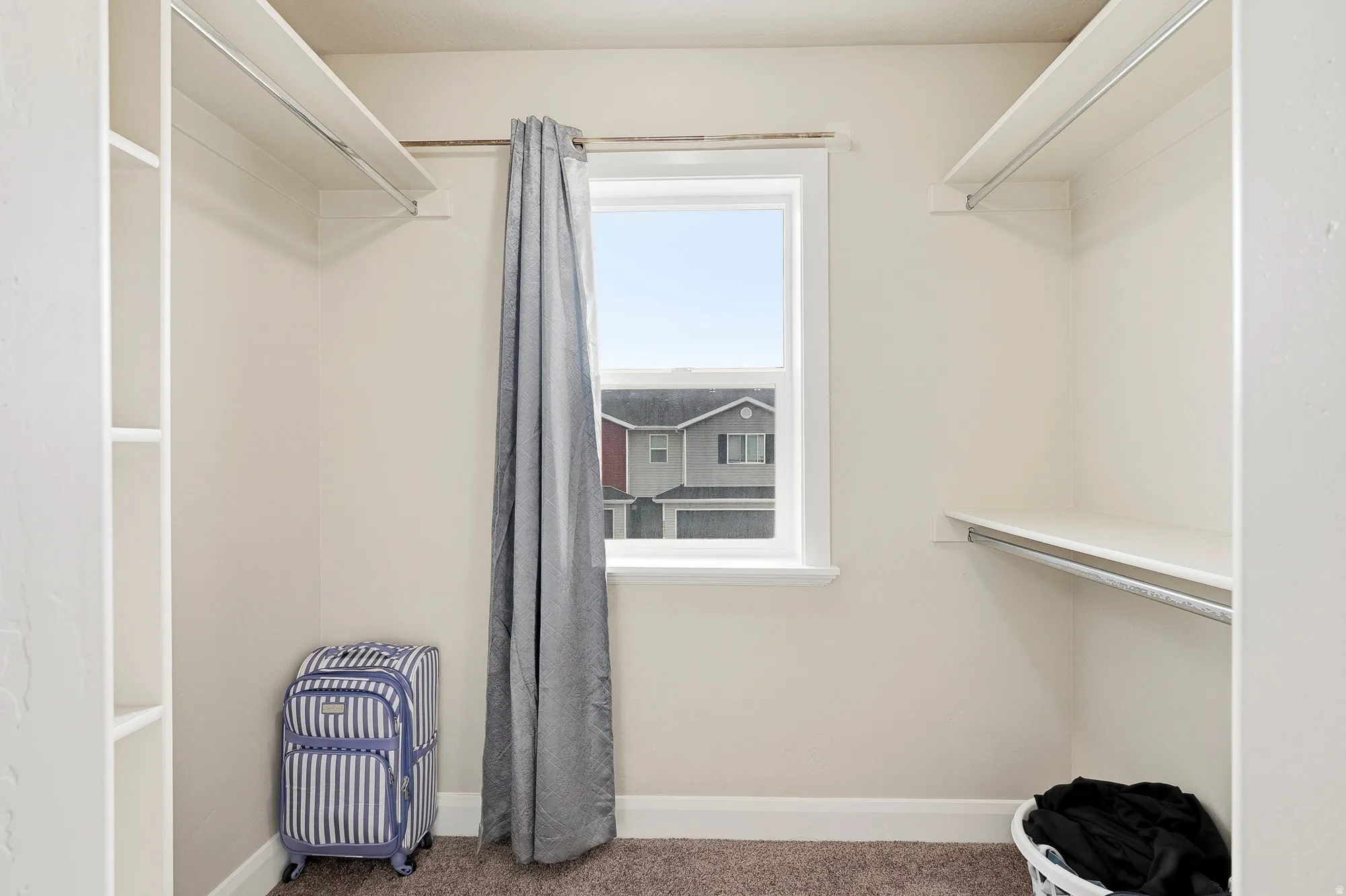 Walk-in closet featuring a window, built-in shelving, and hanging rods