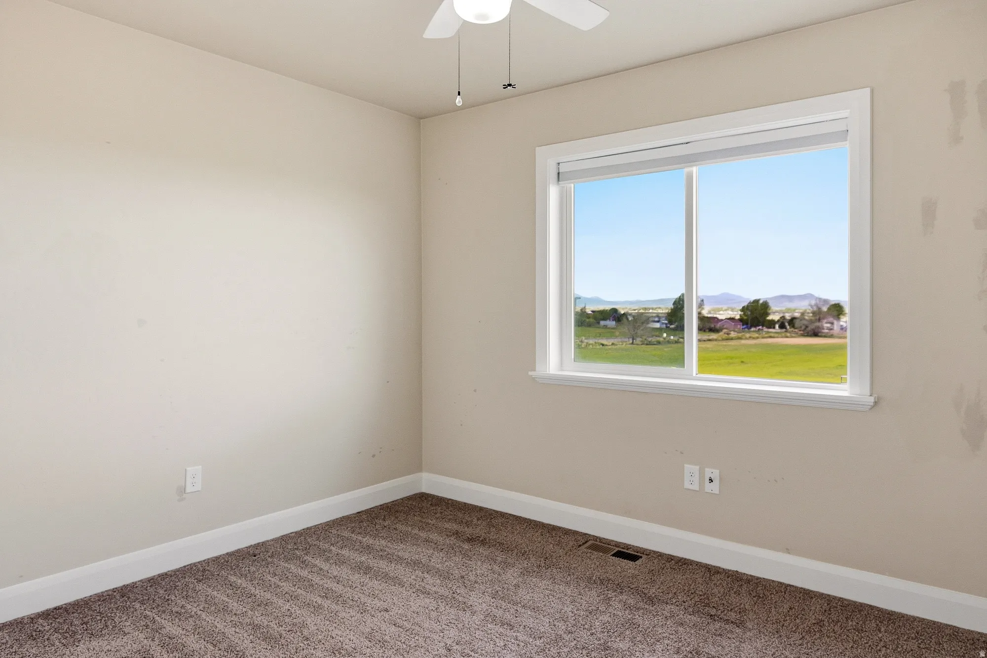 Carpeted spare room featuring a mountain view and ceiling fan