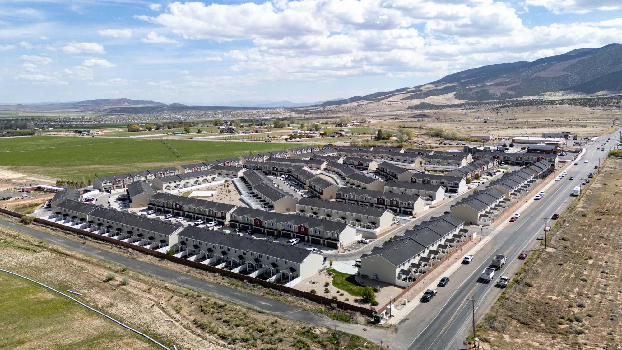 Aerial perspective showcasing a community of townhomes with dark shingle roofs and light-colored siding