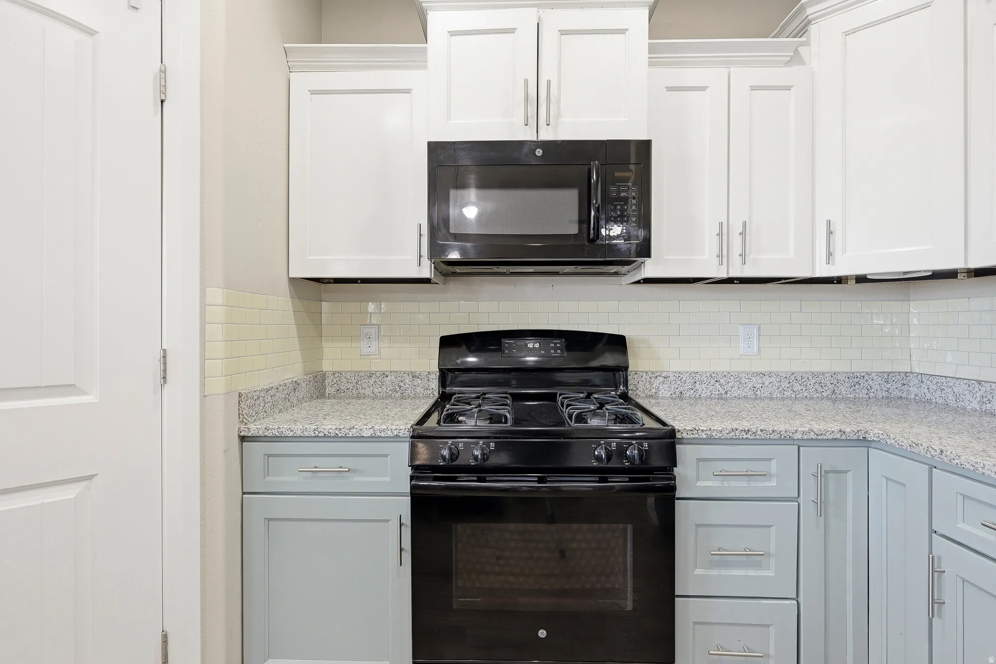 Kitchen featuring a black gas range, built-in microwave, and subway tile backsplash