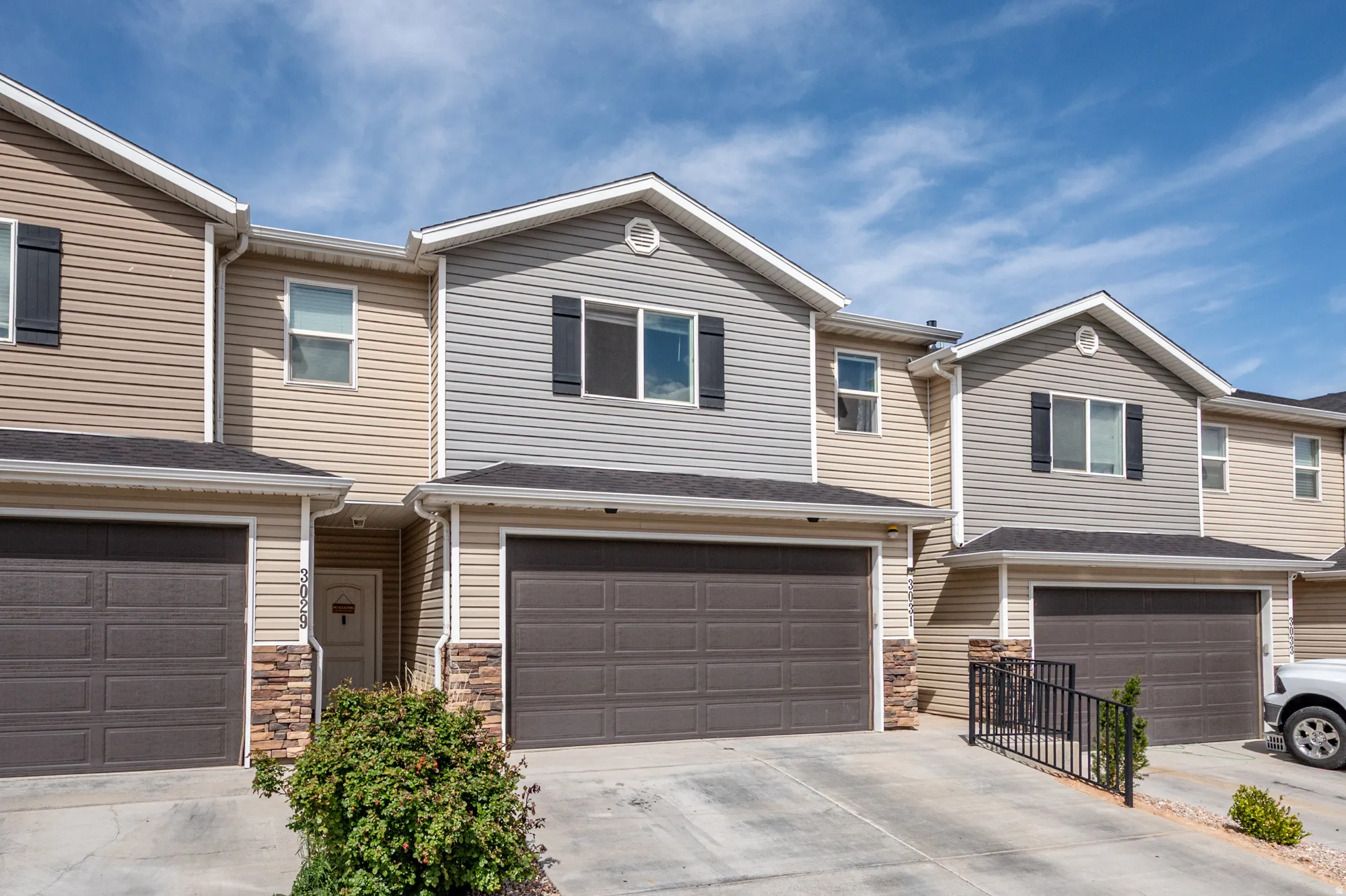 View of front of property featuring stone siding, concrete driveway, and a garage