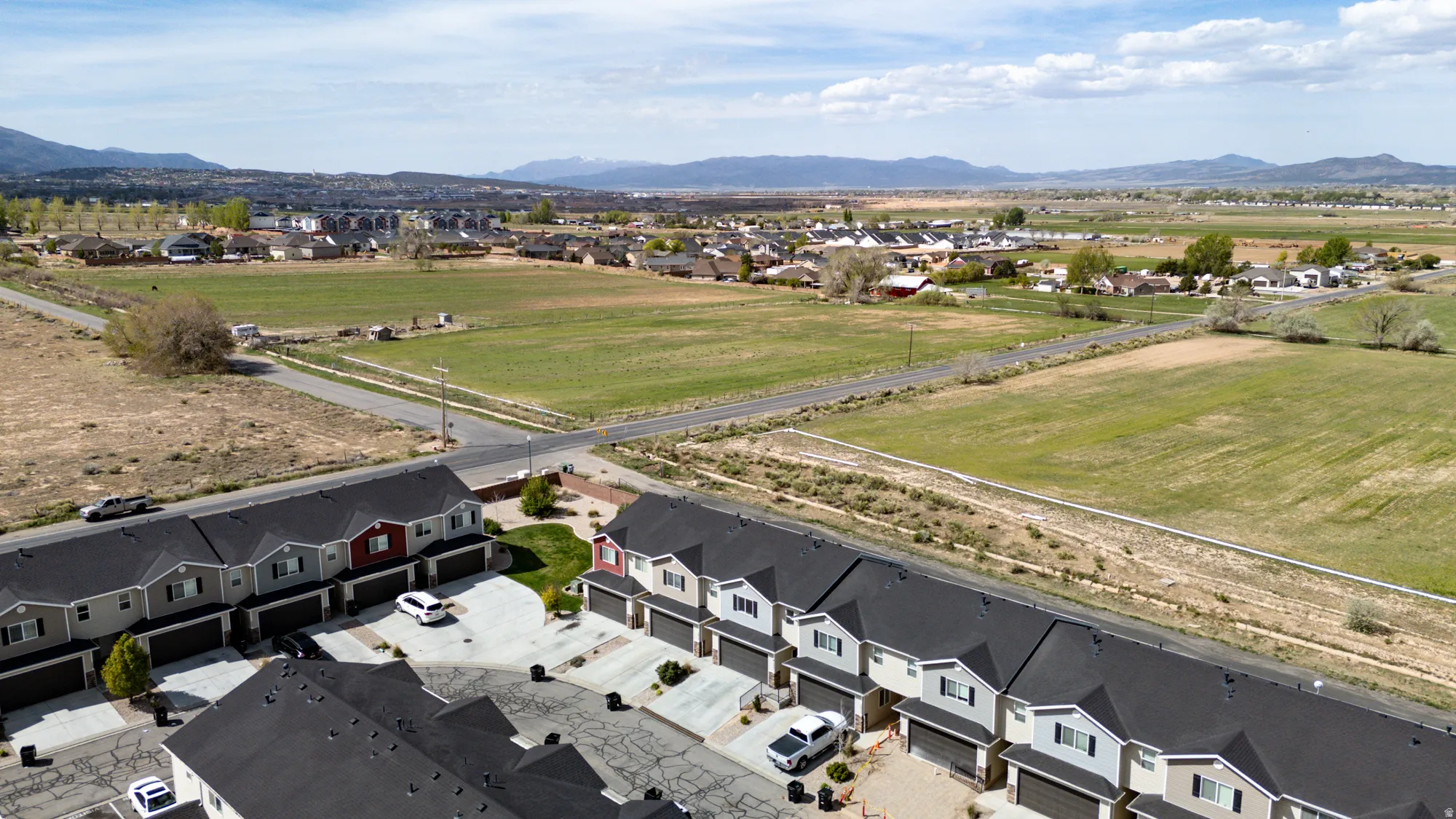 Aerial perspective showcasing a row of residential townhomes with dark shingle roofs and integrated garages