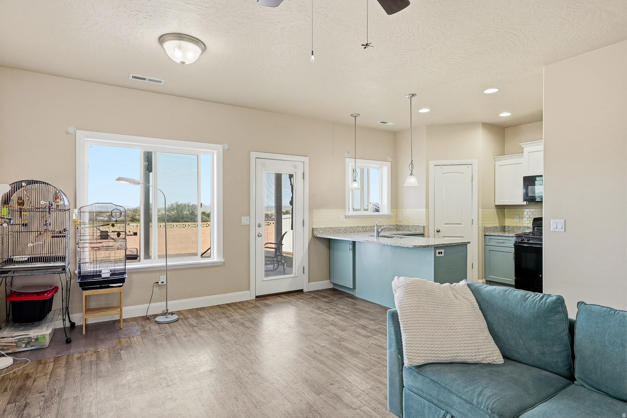 Kitchen with decorative backsplash, a peninsula, open floor plan, black appliances, and light wood finished floors