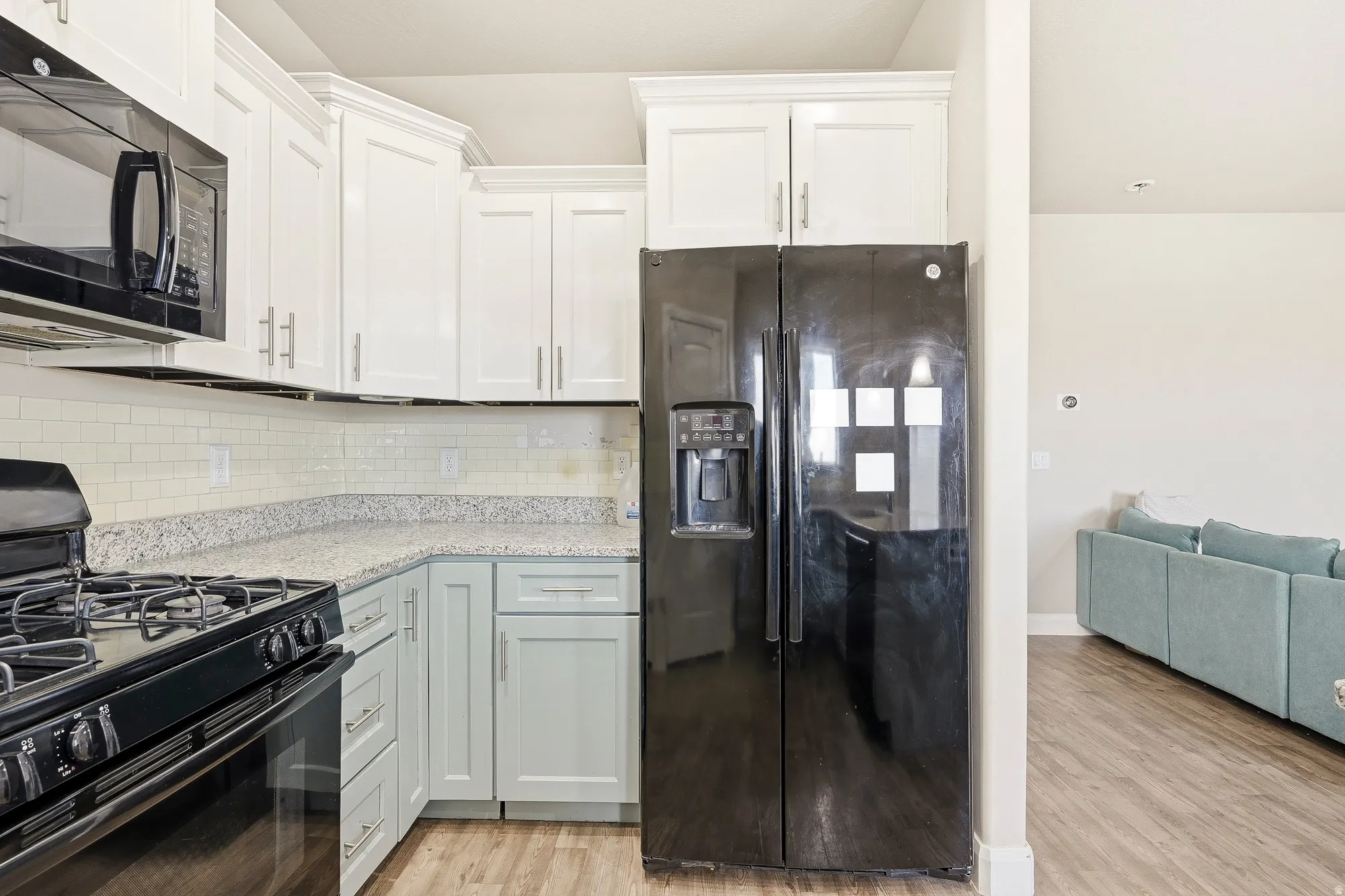 Kitchen featuring a black range and microwave, white subway tile backsplash, and light-toned countertops