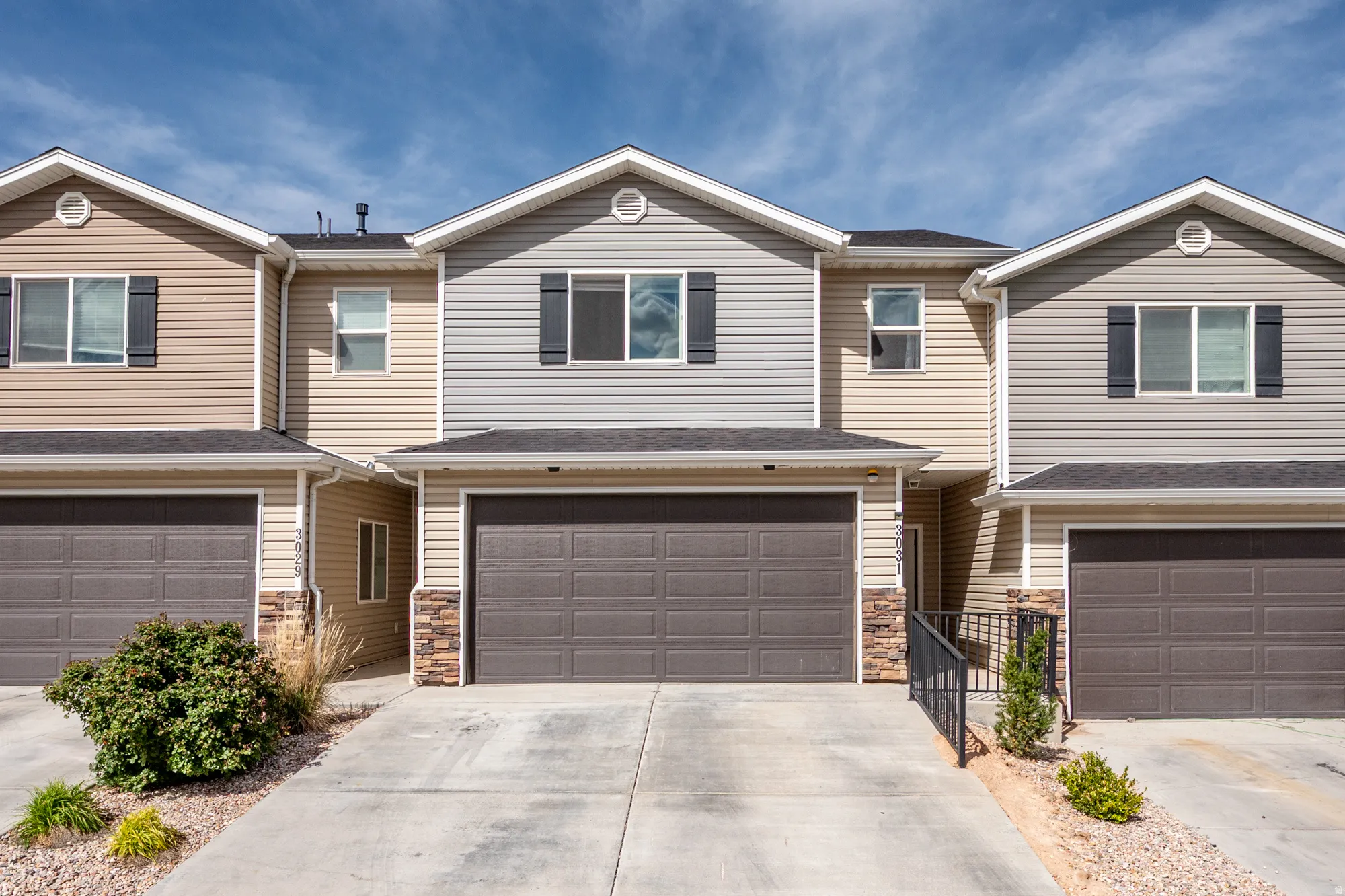 View of front of home with an attached garage, stone siding, driveway, and a shingled roof