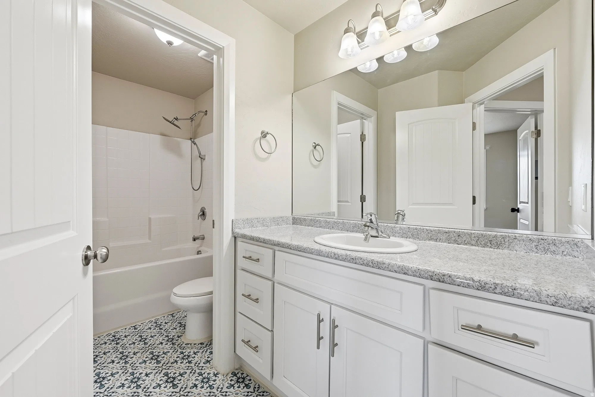 Bathroom featuring a white vanity with a light-toned countertop, a full-width mirror, and a modern light fixture
