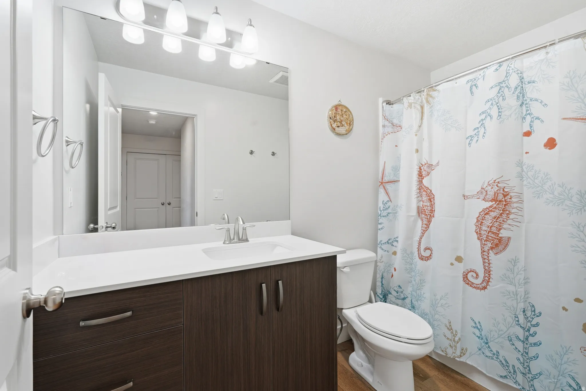 Full bathroom featuring vanity, curtained shower, and dark wood-style flooring