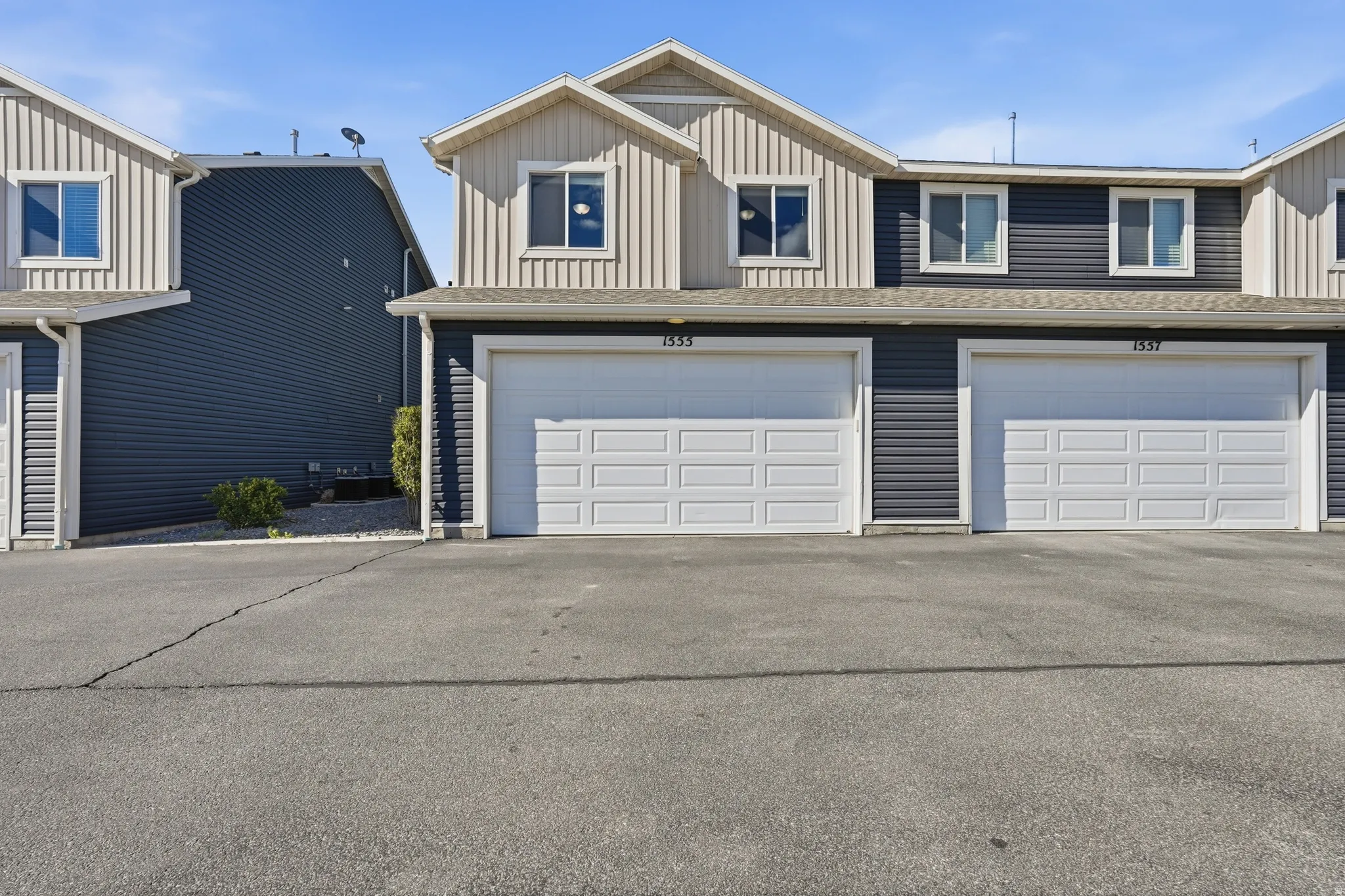 View of front of house with board and batten siding, an attached garage, and asphalt driveway