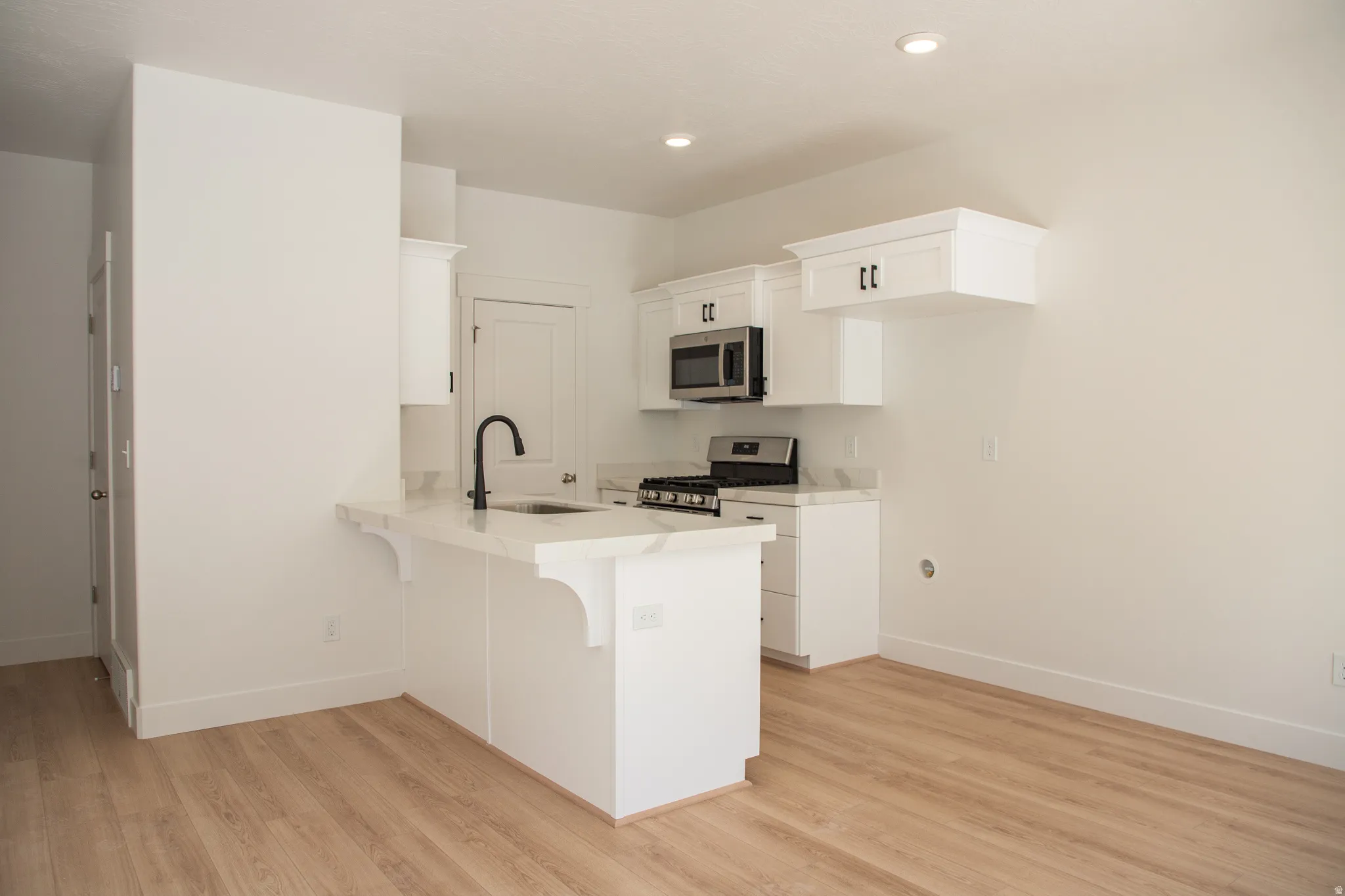 Kitchen with upgraded white cabinets, quartz countertops, and stainless steel appliances
