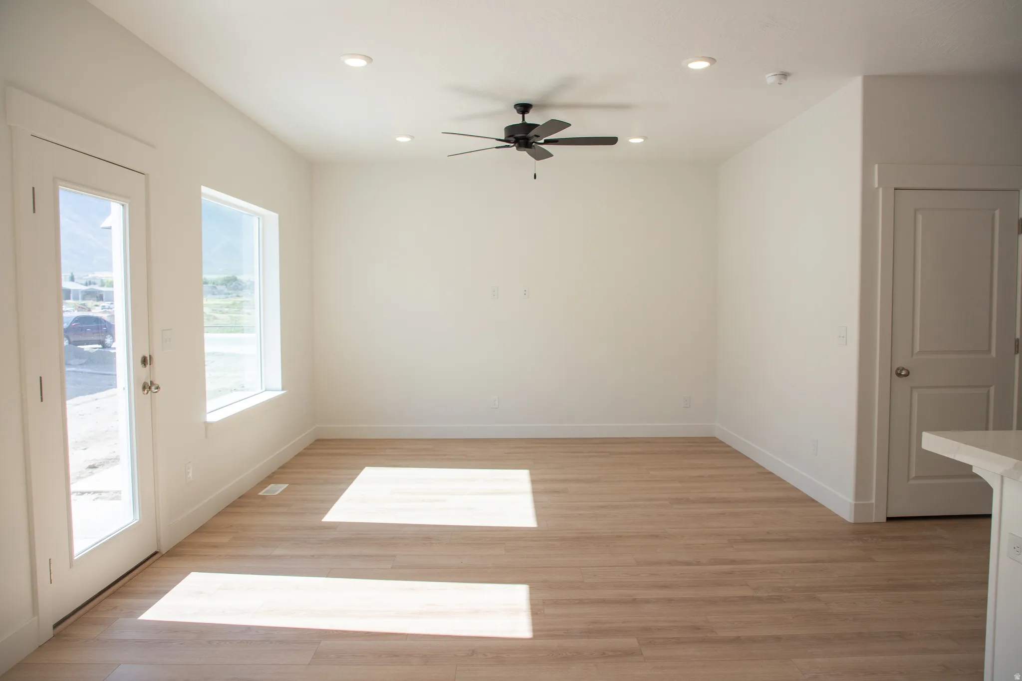 Family room with a ceiling fan, wood laminate flooring, and recessed lighting