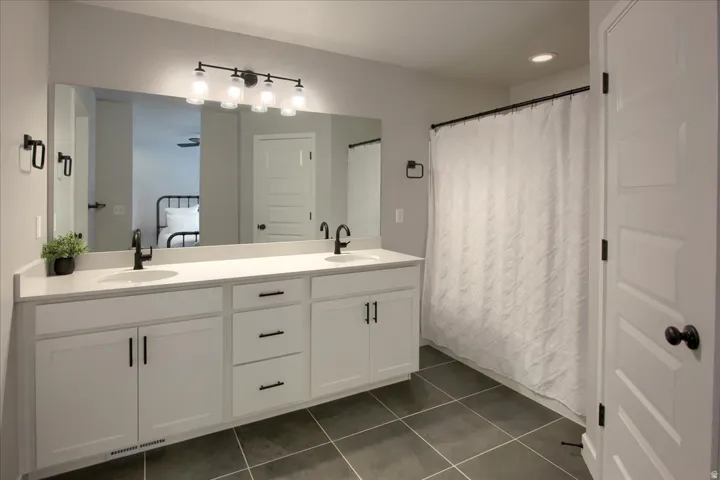 Bathroom with double vanity, dark tile patterned floors, ensuite bath, and recessed lighting