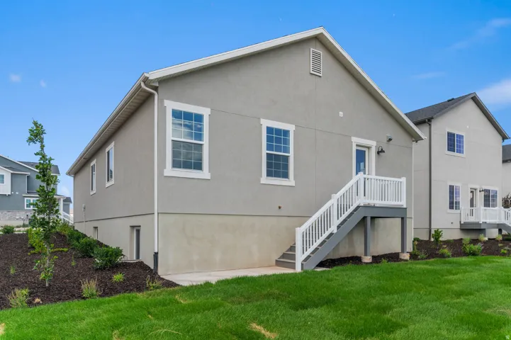 Rear exterior featuring a grey stucco finish and white trim windows