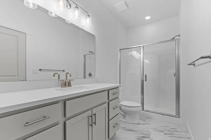 Bathroom featuring a spacious vanity with an undermount sink, brushed nickel faucet, large mirror, and contemporary light fixture