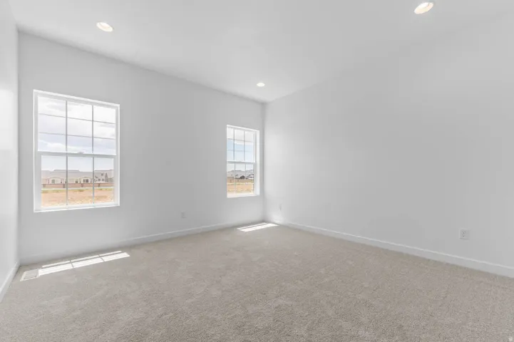 Spacious room featuring neutral carpeting, recessed ceiling lighting, and two multi-pane windows