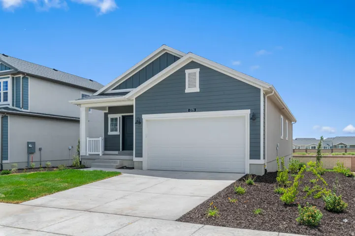 Modern ranch-style home featuring a two-car garage, covered porch, partial stone retaining wall, and landscaped front yard with a concrete driveway