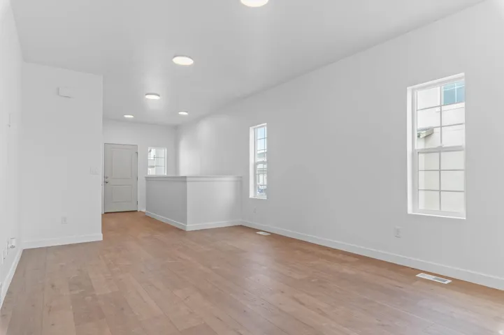 Spacious interior featuring wood-finish flooring, white baseboards, and crisp white walls