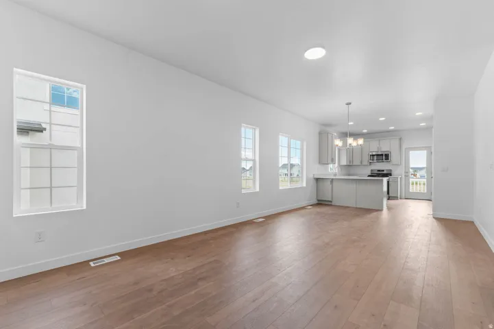 Open-concept living area featuring wood-finish flooring, multiple windows, and recessed lighting