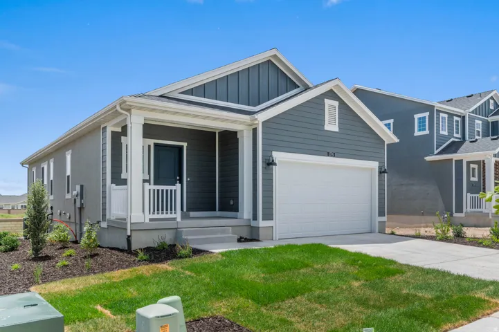 Contemporary exterior featuring a covered porch with white railing, a dark paneled front door, an attached garage, and a concrete driveway