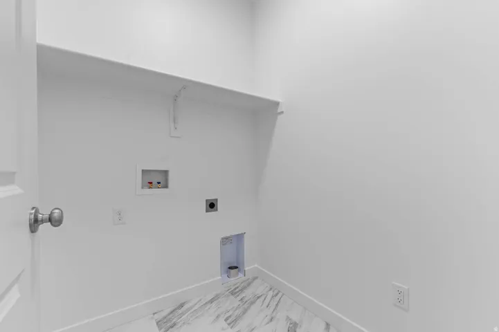 Laundry area with a wall-mounted shelf, white trim, and a utility hookup