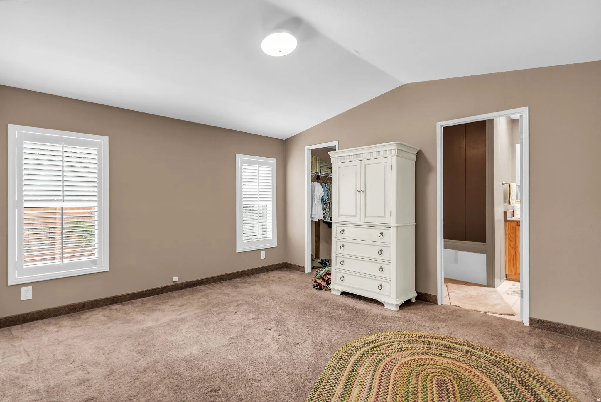 Unfurnished bedroom with light colored carpet and baseboards