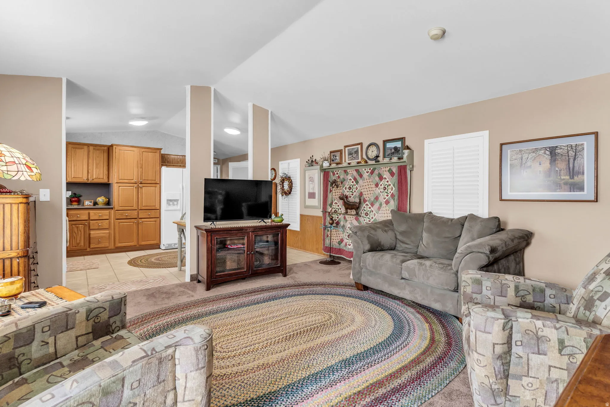 Living area with lofted ceiling, light colored carpet, and light tile patterned floors
