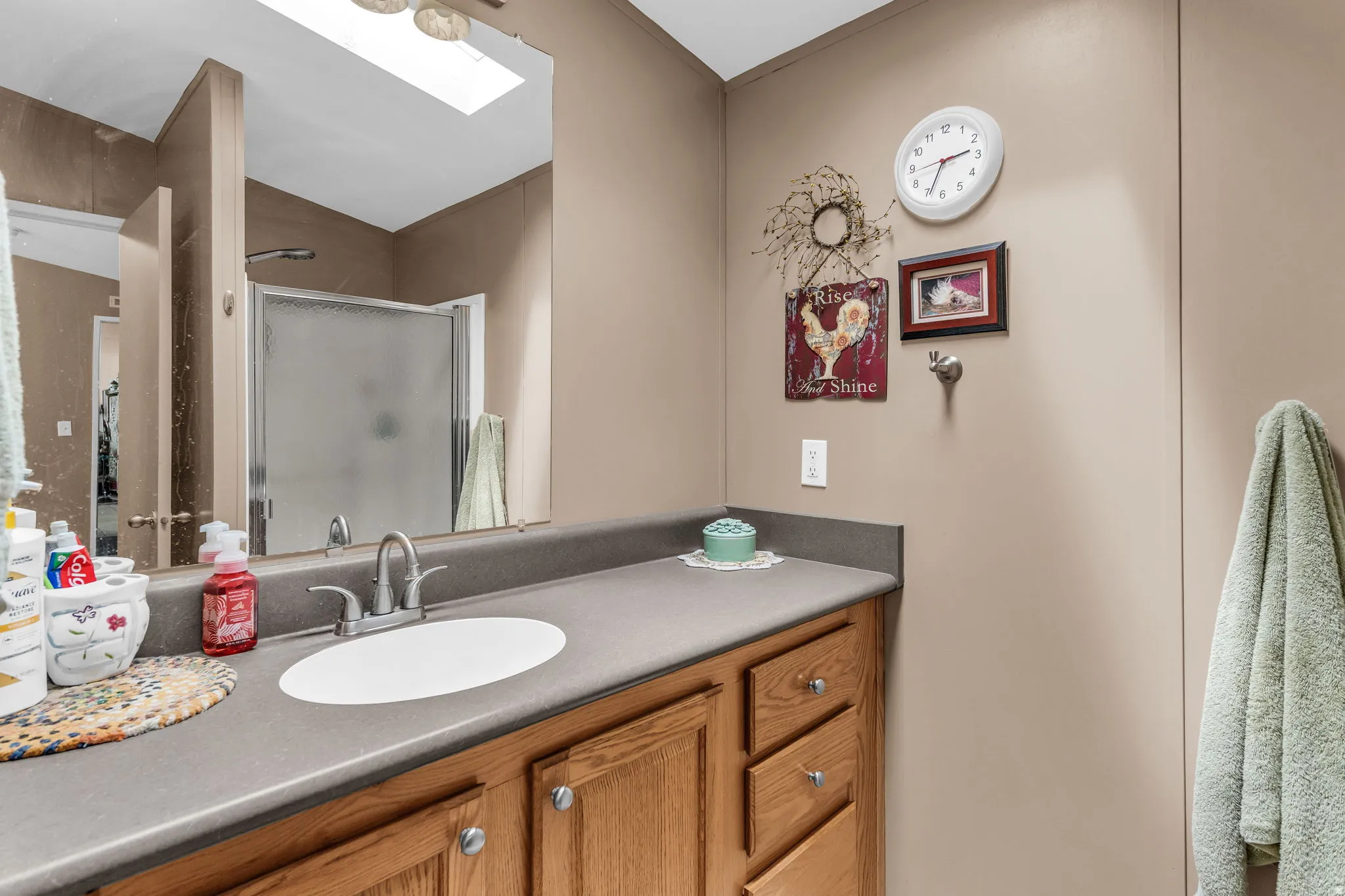 Bathroom with a skylight, a shower stall, and vanity