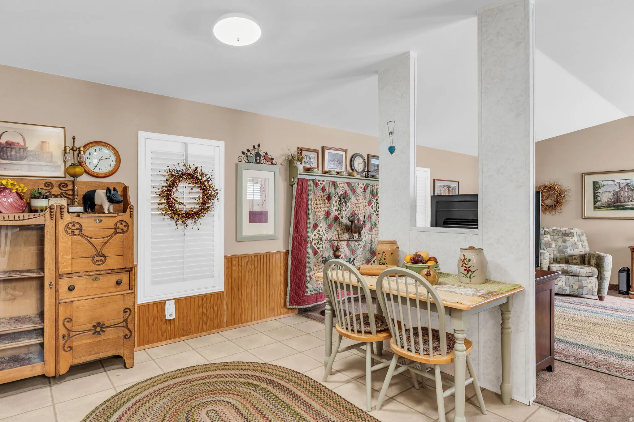 Dining area featuring wainscoting, wood walls, light tile patterned floors, and vaulted ceiling