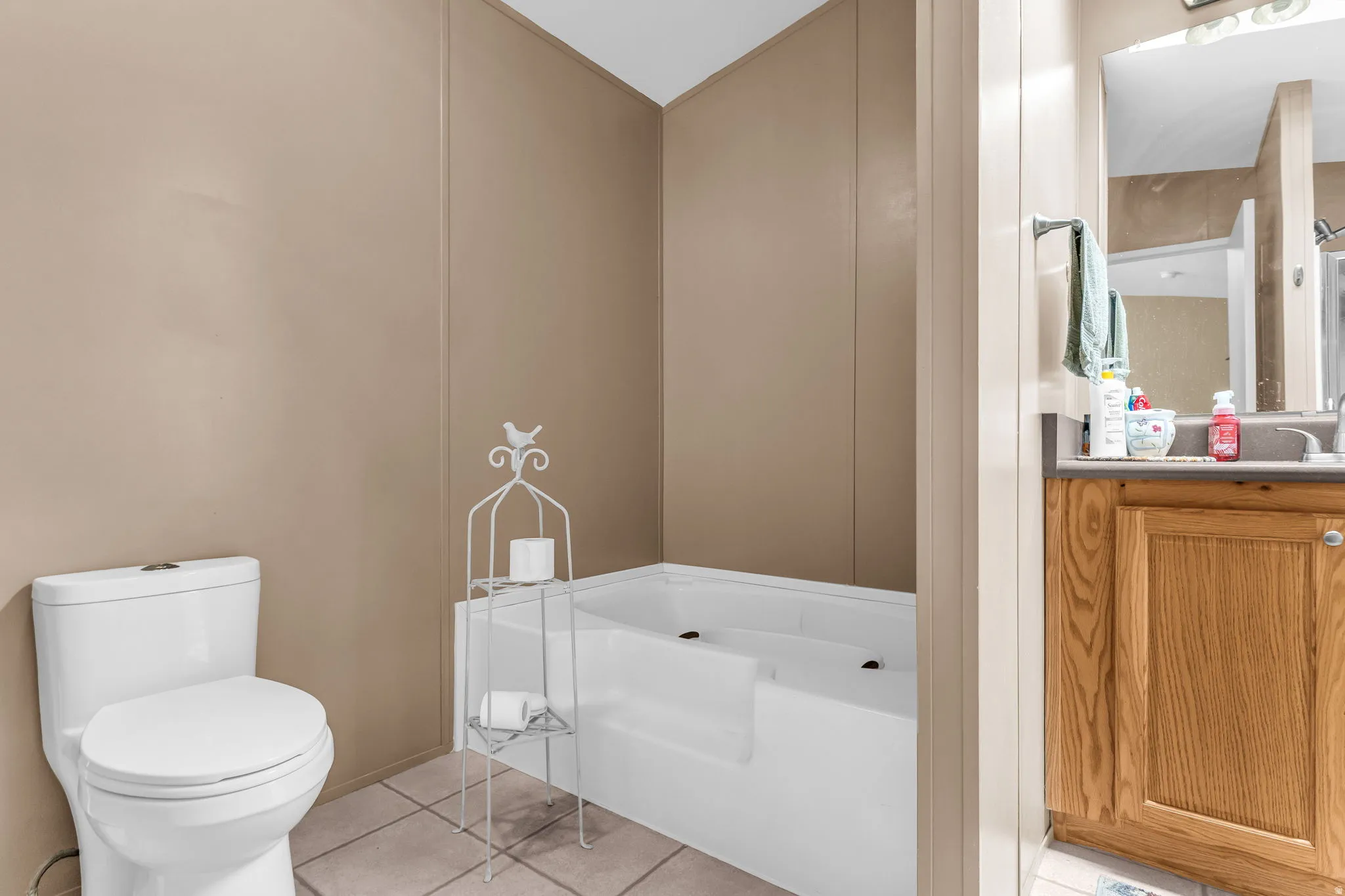Bathroom featuring a bath, light tile patterned floors, vanity, and a decorative wall