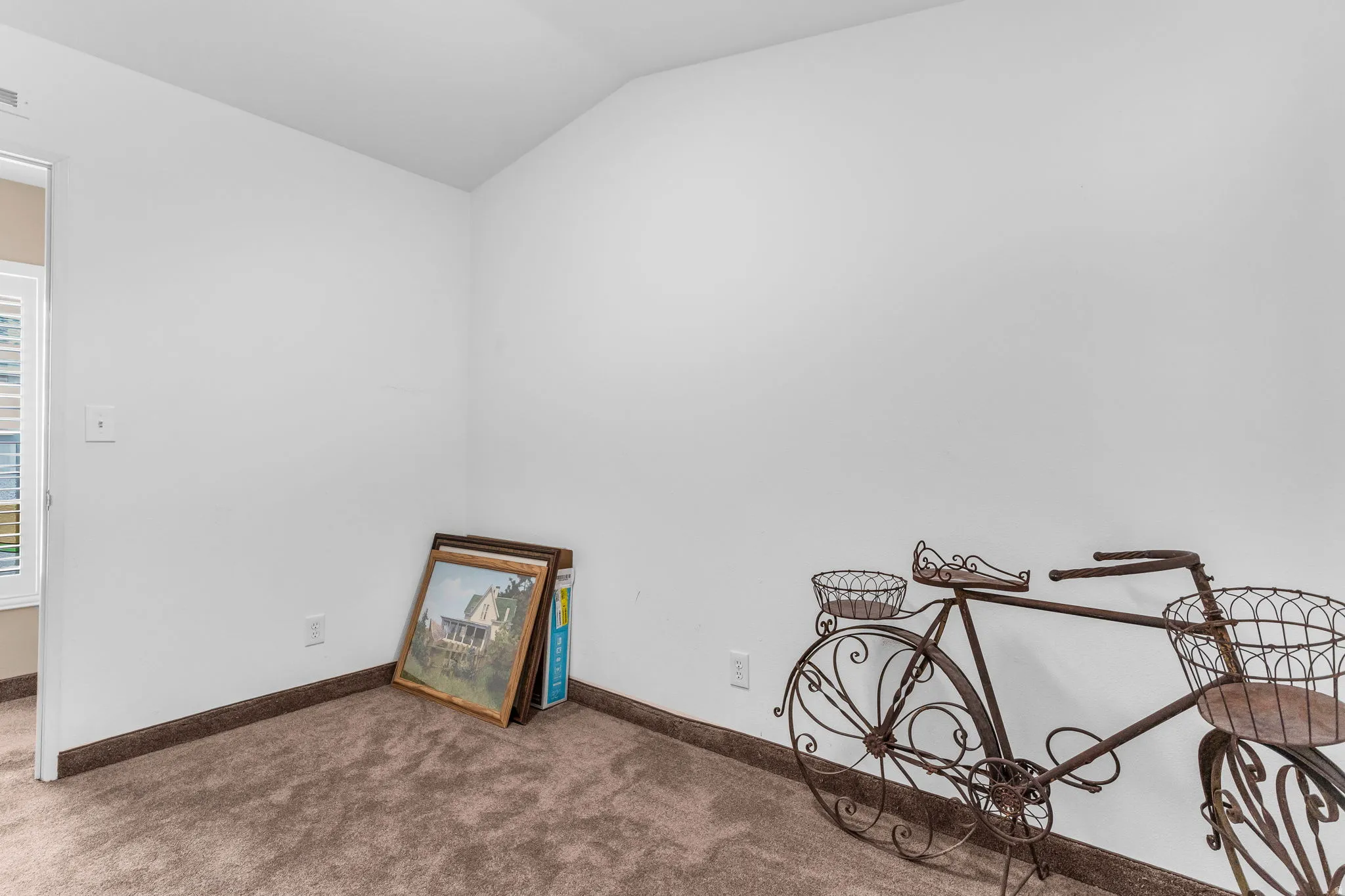 Carpeted empty room featuring lofted ceiling and baseboards