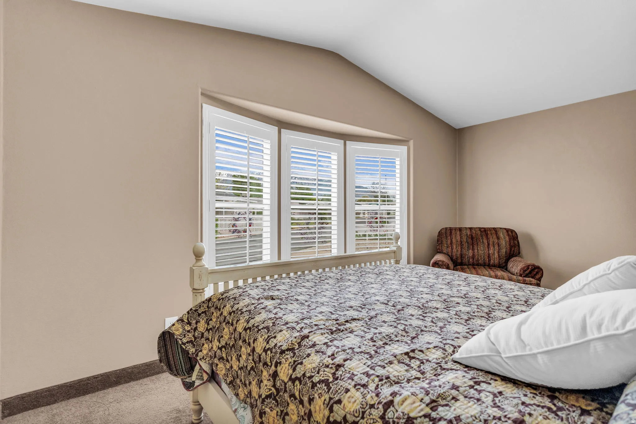 Carpeted bedroom with vaulted ceiling and baseboards