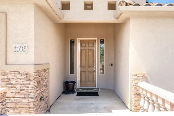 Doorway to property with stone siding, stucco siding, and a porch