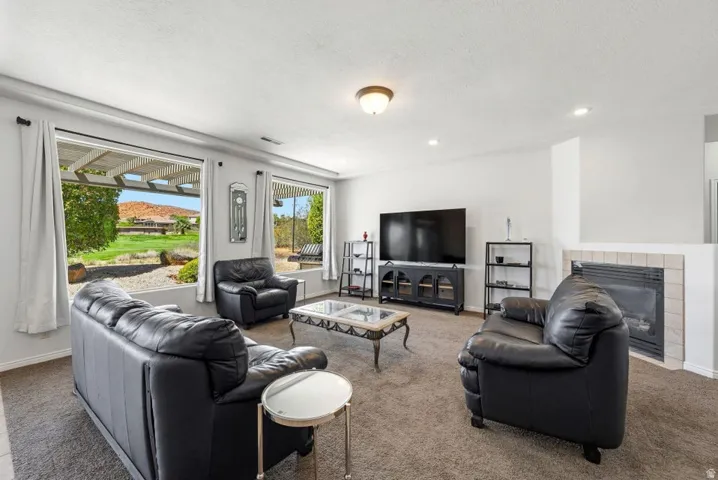 Living area featuring a tiled fireplace, carpet floors, and recessed lighting